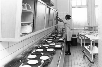 826899 Interieur van de Emmakliniek (Koningslaan 81) te Utrecht: de keuken waar een verpleegkundige borden klaar ...